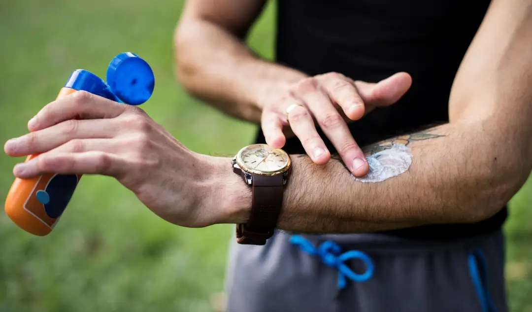 Person applying insect repellent to their forearm outdoors